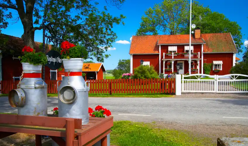 Ett rött hus med ett vitt staket och en silverföremål med blommor.